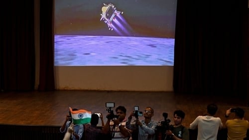 Daoine in Mumbai ag faire ar bheoshruth de thuirlingt Chandrayaan-3 ar an ngealach