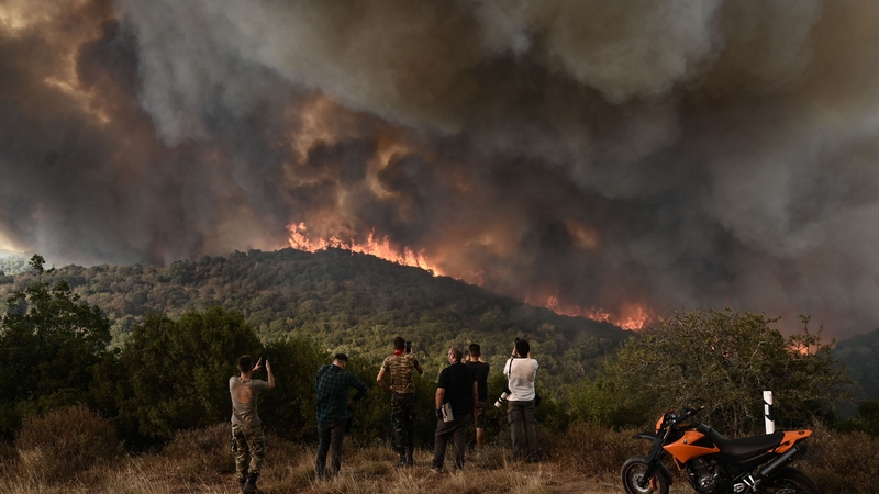 People look at the wildfire raging in a forest in Sikorahi, near Alexandroupolis