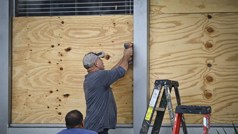 People board up a window in Tampa, Florida, as the city prepares for Hurricane Idalia.