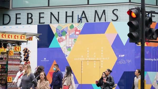 Shoppers walking past the boarded-up former Debenhams flag-ship store in Oxford Street, London