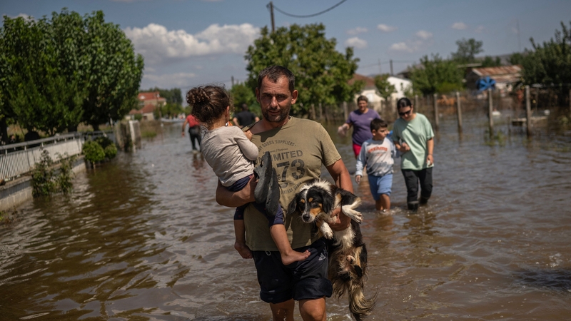 A man carries a girl and a dog in the flooded village of Palamas near the city of Karditsa