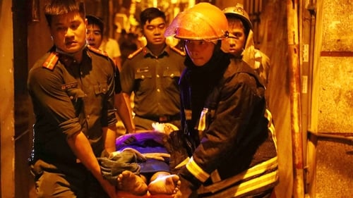 Rescue workers carrying a survivor following the fire at an apartment block in Hanoi