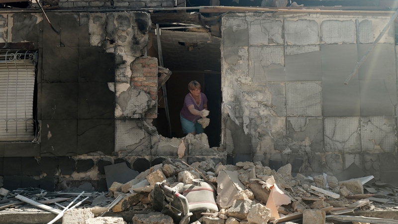 A local resident clear debris in her house destroyed as a result of missiles strike to Kherson earlier this month
