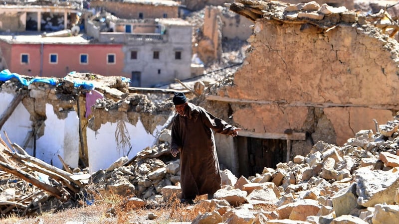A man walks past debris from destroyed buildings in the village of Ardouz