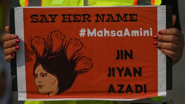A demonstrator holds a poster at a protest to remember Jina Mahsa Amini in Edmonton, Alberta, Canada