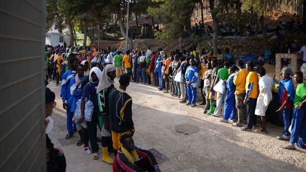 Migrants queue at a camp in the harbour of the Italian island of Lampedusa yesterday
