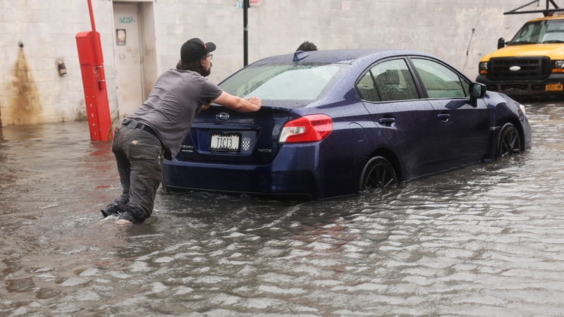 A car is pushed through flooded streets in the Red Hook neighborhood on in the Brooklyn borough of New York City