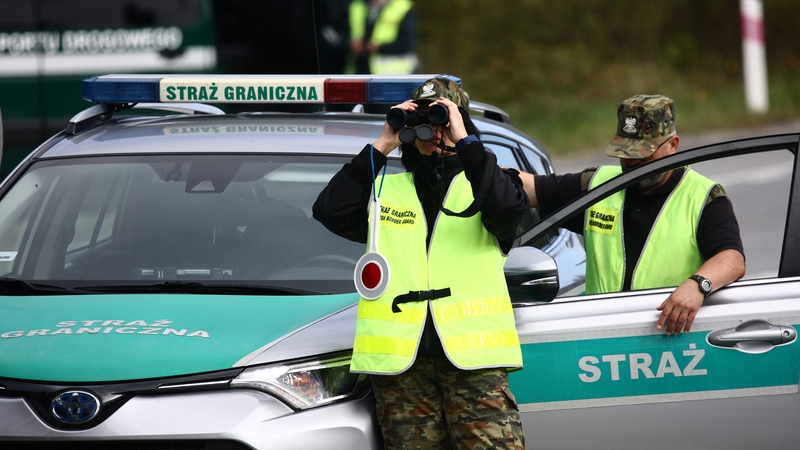A Polish border guard uses binoculars to observe the border line in Chyzne