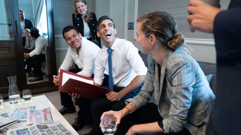 Rishi Sunak poses for photographs as he meets staff in his room at the party conference in Manchester