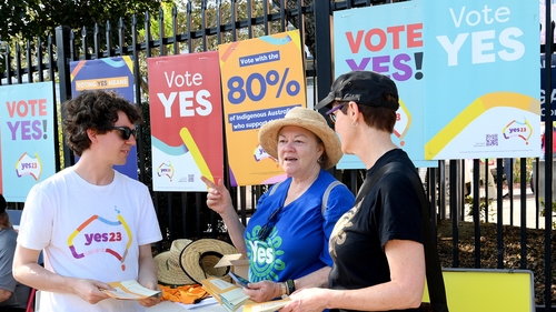 A voter is seen chatting to 'Yes' voting campaigners at a polling centre in Brisbane