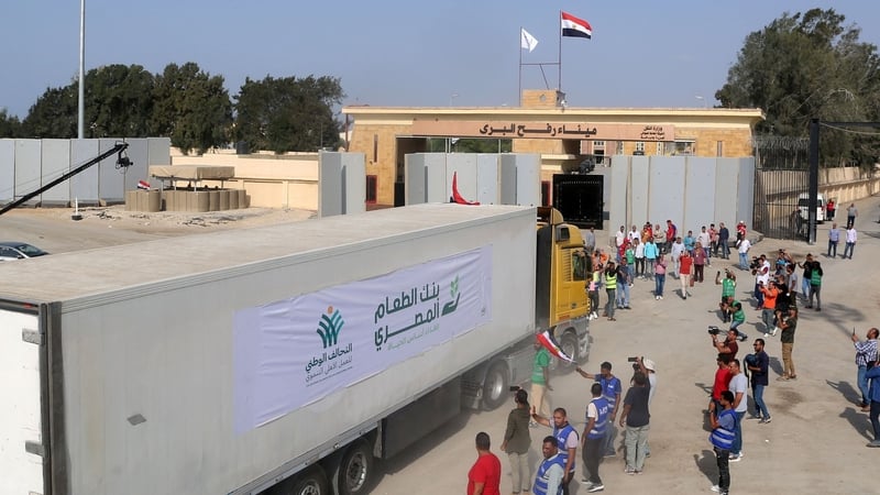 People on the Egyptian side of the Rafah border crossing watch as a convoy of lorries carrying humanitarian aid crosses into Gaza