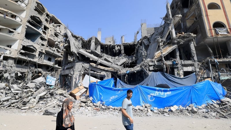 Palestinians walk past a building damaged in an Israeli air strike in Khan Yunis
