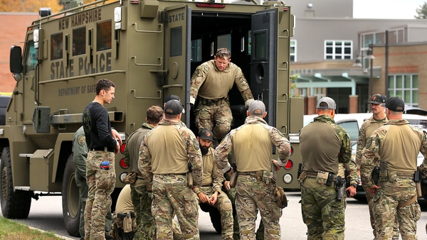 New Hampshire State Police meet behind an armoured vehicle at Lewiston High School which is serving as a staging area for law enforcement