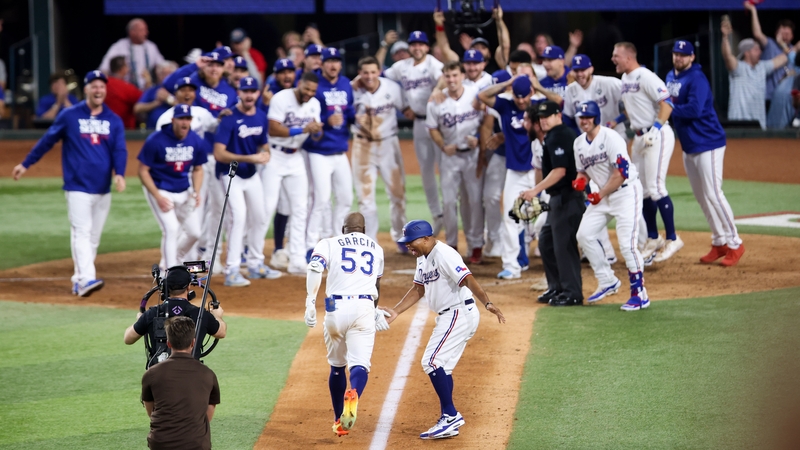 Adolis Garcia's team-mates wait for him at home plate after he scored the winning run