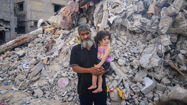 A Palestinian man and child beside the rubble of destroyed buildings following an Israeli missile strike in the center of Khan Younis