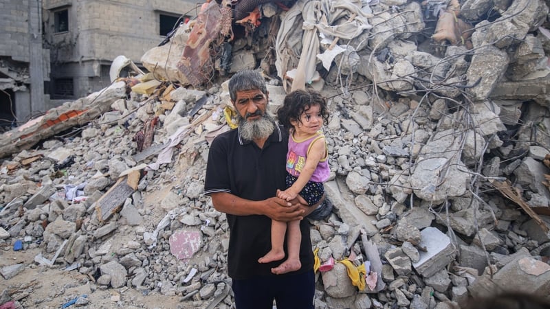 A Palestinian man and child beside the rubble of destroyed buildings following an Israeli missile strike in the center of Khan Younis