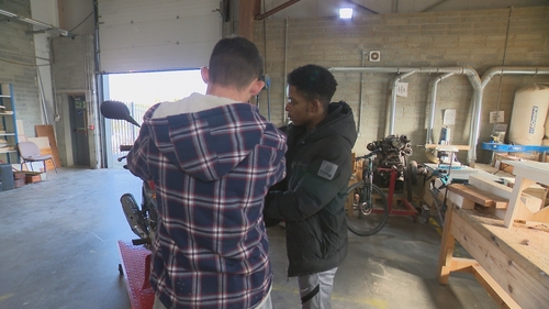 Participants involved in motorbike repair work at Treo