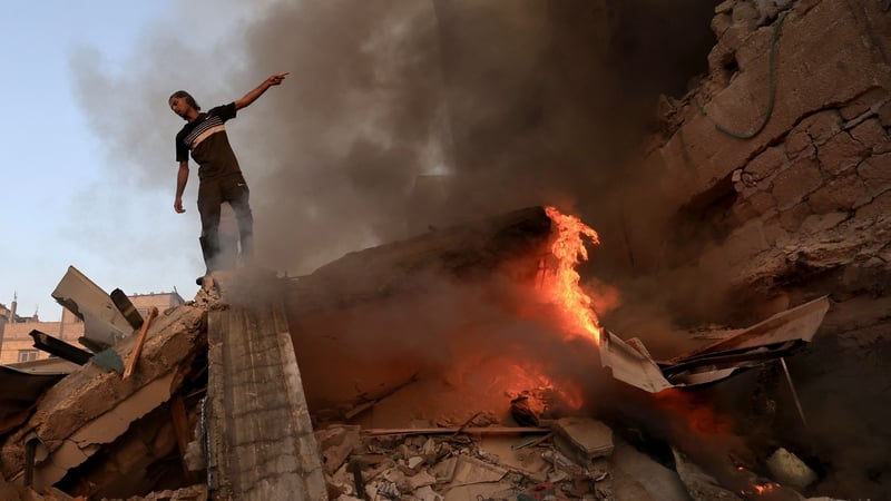 A man gestures as he stands on the rubble of a collapsed building in Khan Yunis