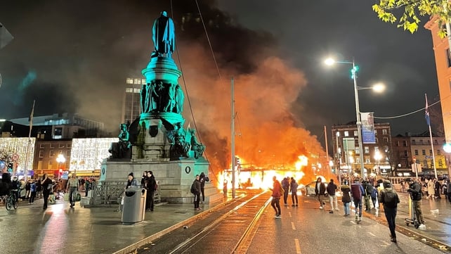 A bus is on fire on Dublin's O'Connell Street during a night of unrest in the city centre. The unrest started following a knife attack in which three children and a woman were injured. A Luas tram was also set alight while some shops were looted.