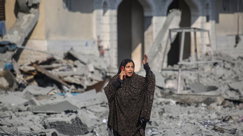 A Palestinian woman standing outside destroyed buildings after an Israeli airstrike