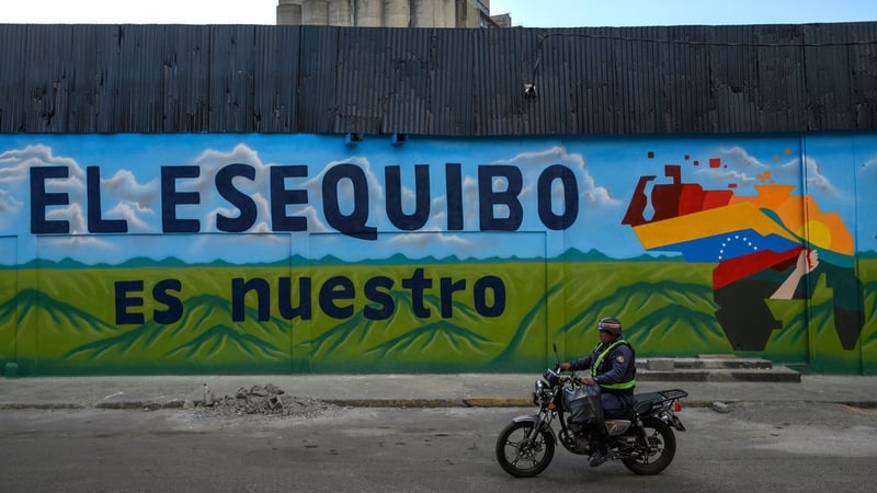 A man drives past a mural that reads 'The Essequibo Is Ours' in Caracas, Venezuela