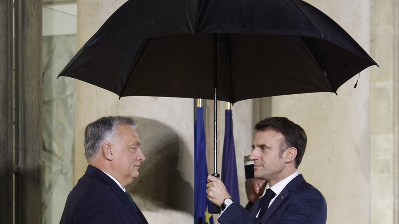 Emmanuel Macron (R) shields Viktor Orban from the rain at the Elysée Palace