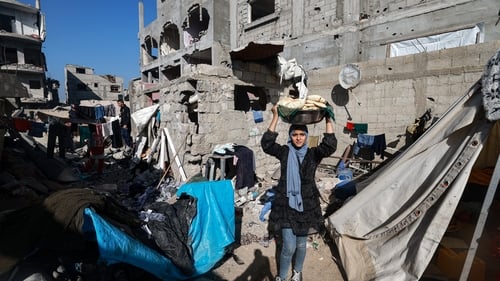 A woman carries bread next to destroyed houses in Rafah in southern Gaza