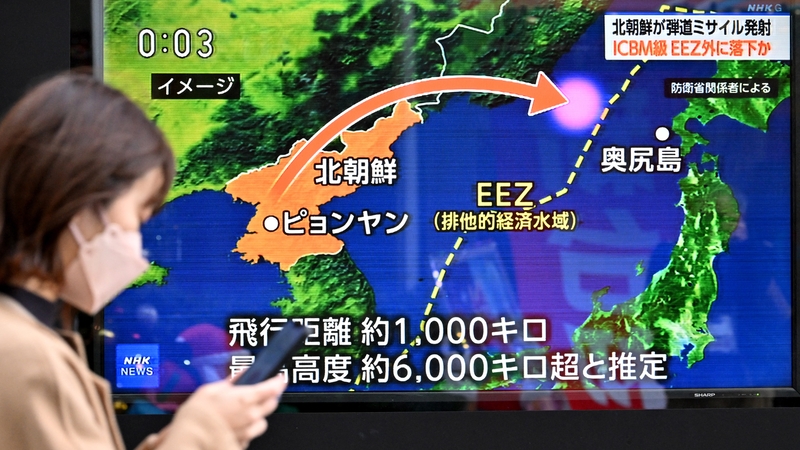 A pedestrian walks past a television screen broadcasting a news report on the North Korean missile launch in Tokyo this morning