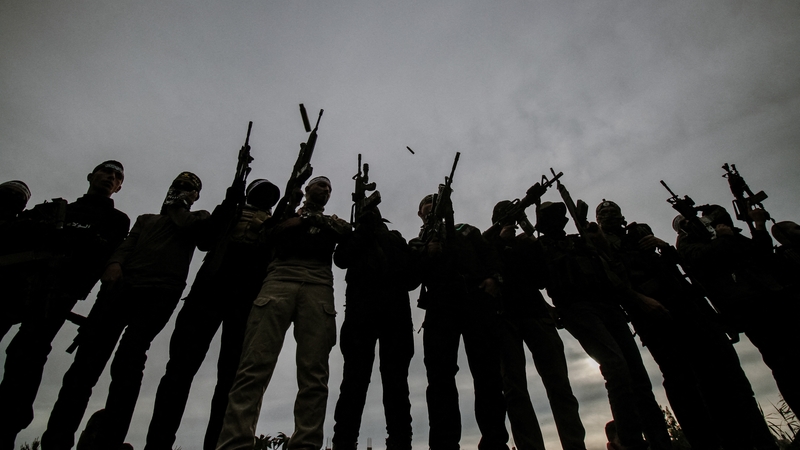 Men hold weapons in the air during funerals for five people killed in a Israeli raid on Nur Shams refugee camp in the West Bank on 17 December