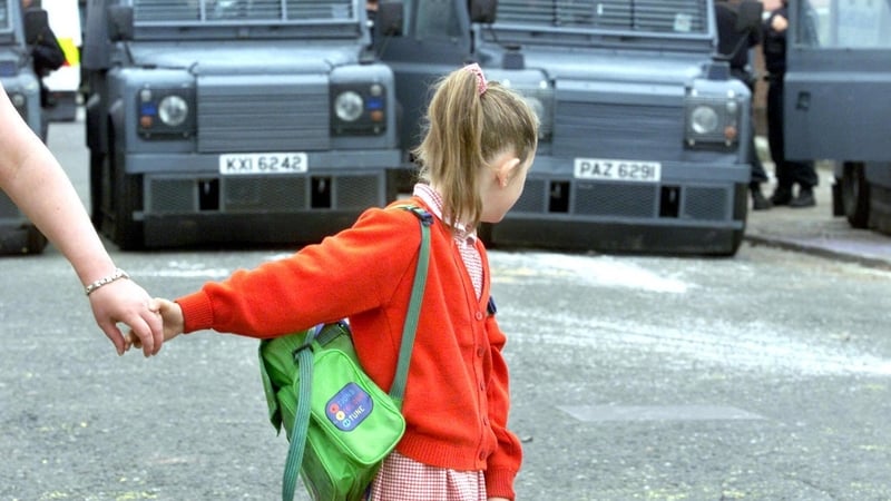 Seven year old Leona Burns is led away from a police line of Land Rovers which is blocking her route to Holy Cross Primary School, 22 June, 2001