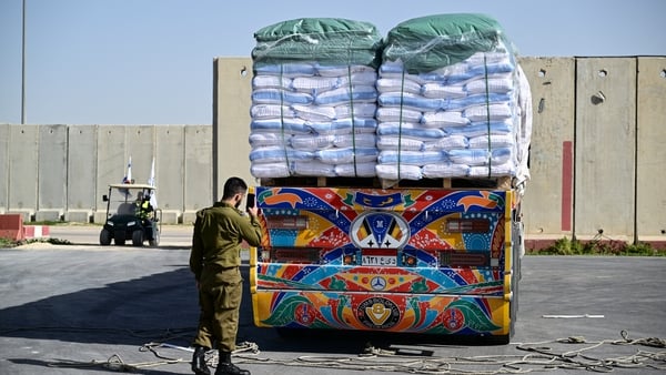 A member of Israeli security forces inspects humanitarian aid trucks arriving from Egypt on the Israeli side of the Kerem Shalom border crossing
