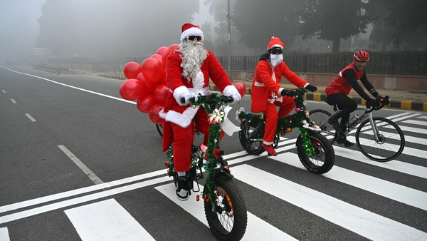 People dressed in santa outfits cycle through the smog of New Delhi in India