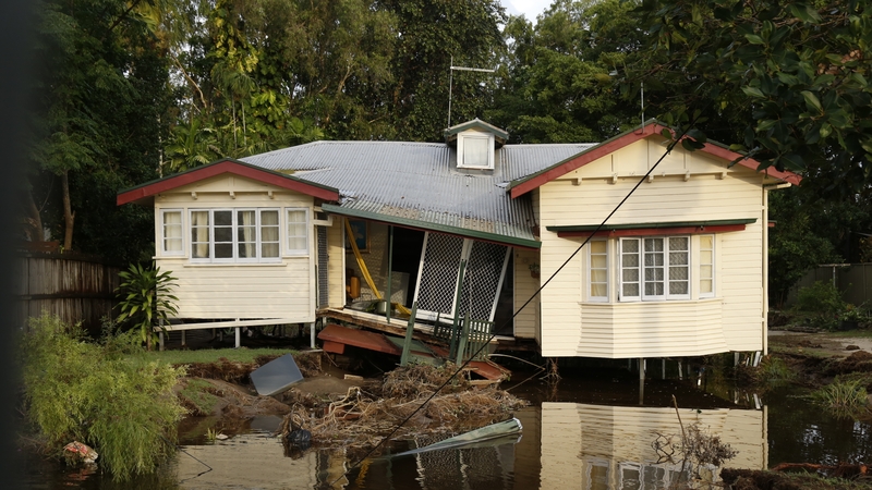 A house and road has partially collapsed, bring down power lines and poles in the Cairns suburb of Holloways Beach after major flooding