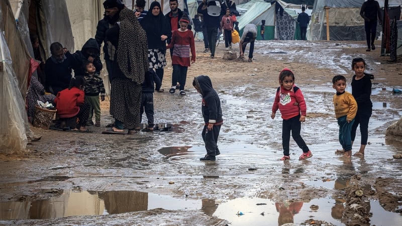 Children walk amongst puddles of water in the makeshift refugee camp in Rafah