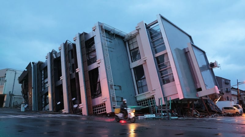 A man on a scooter passes a collapsed multi-storey building in the city of Wajima, Ishikawa prefecture