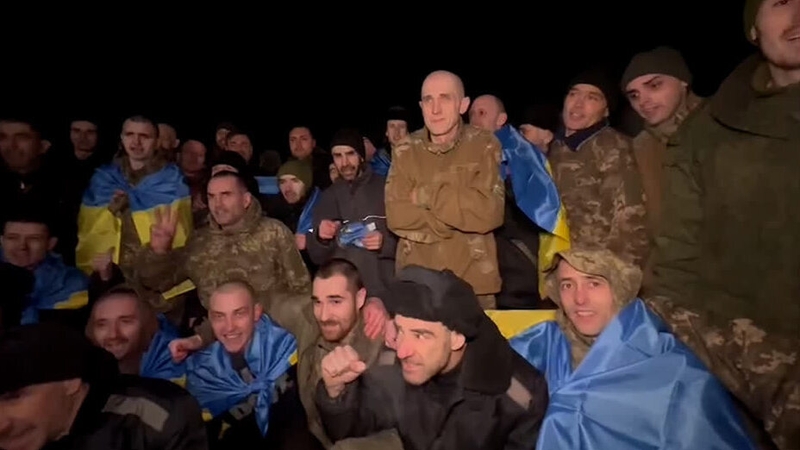 A group of men, some wrapped in Ukrainian flags, are among the prisoners of war released