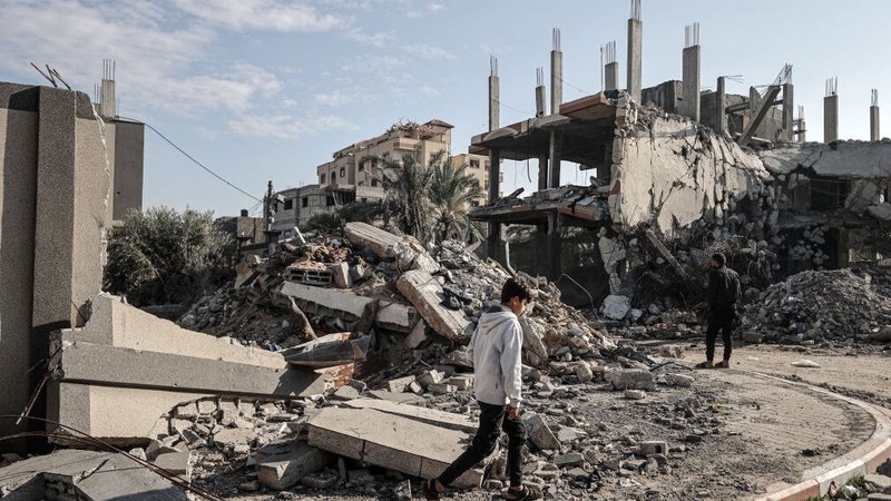 Palestinians are seen next to the rubble of a buildings destroyed by Israeli attacks in Deir al-Balah, Gaza