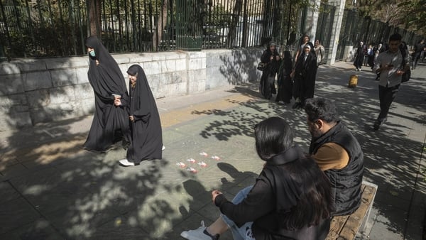 A group of veiled Iranian women walk past a man and a woman not wearing a mandatory headscarf, out of the University of Tehran (file image)