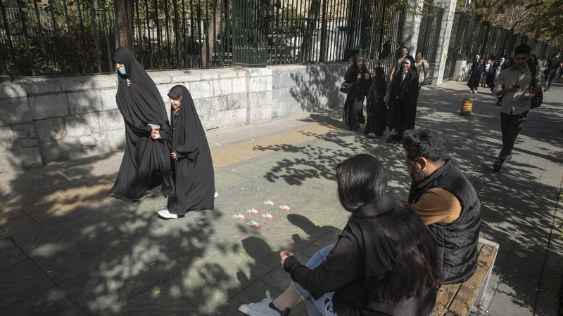 A group of veiled Iranian women walk past a man and a woman not wearing a mandatory headscarf, out of the University of Tehran (file image)