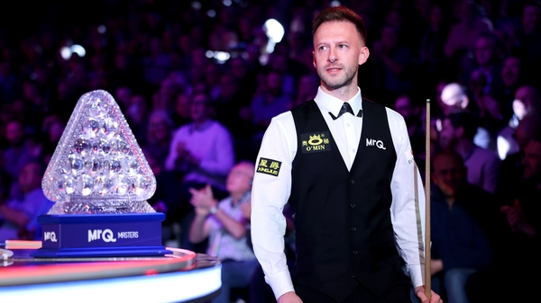 Judd Trump passes the trophy he is defending as he enters the arena ahead of the match