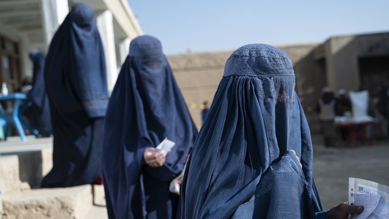 Afghan burqa-clad women queue to receive food from the World Food Programme