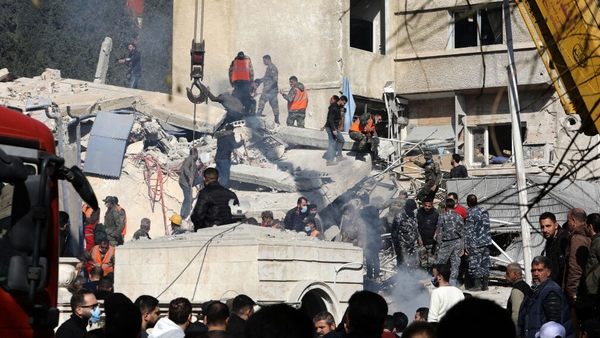 Security and emergency personnel search the rubble of a building destroyed in a reported Israeli strike