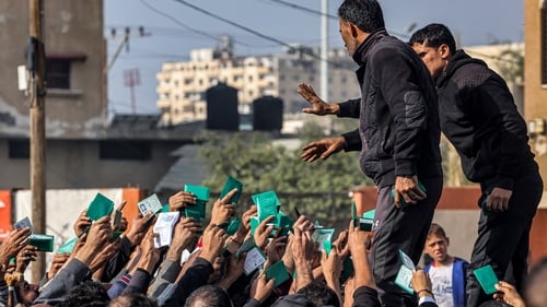 People gather to receive flour rations outside a UNRWA warehouse in Rafah