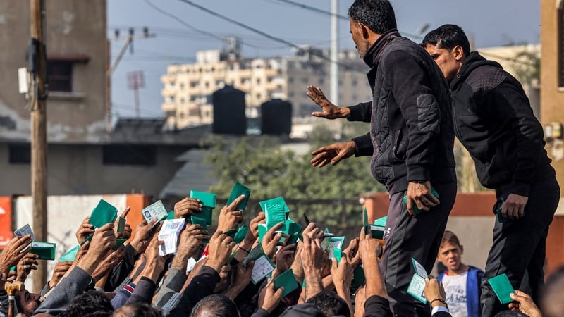 People gather to receive flour rations outside a UNRWA warehouse in Rafah