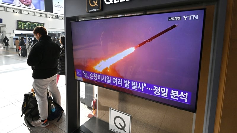 A man stands next to a tv in Seoul showing a news broadcast with file footage of a North Korean missile test