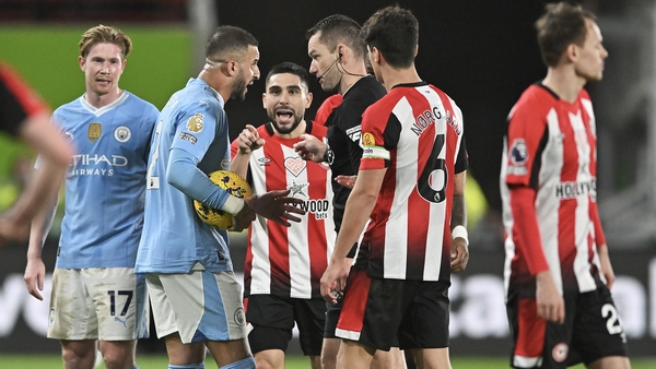 Kyle Walker of Manchester City speaks to referee Jarred Gillett as Neal Maupay of Brentford gestures