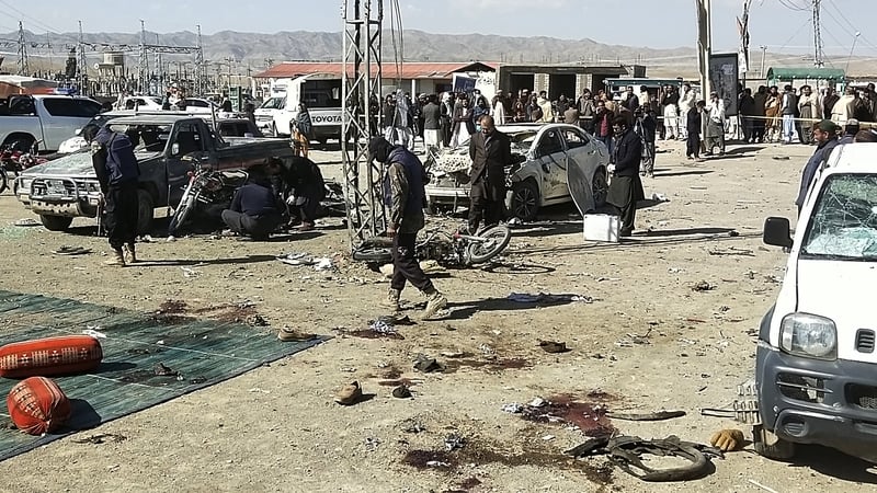 Security personnel inspect the site of a bomb blast outside the office of an independent candidate in the Pishin district