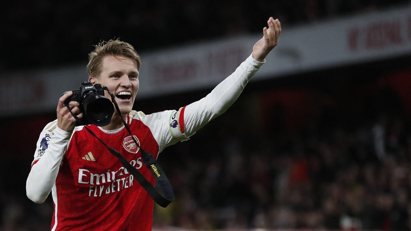 Odegaard picks up a camera and takes pictures as he celebrates after Liverpool win