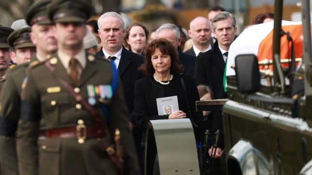 Finola Bruton and Matthew Bruton follow as the coffin is carried by the Defence Forces through Dunboyne village