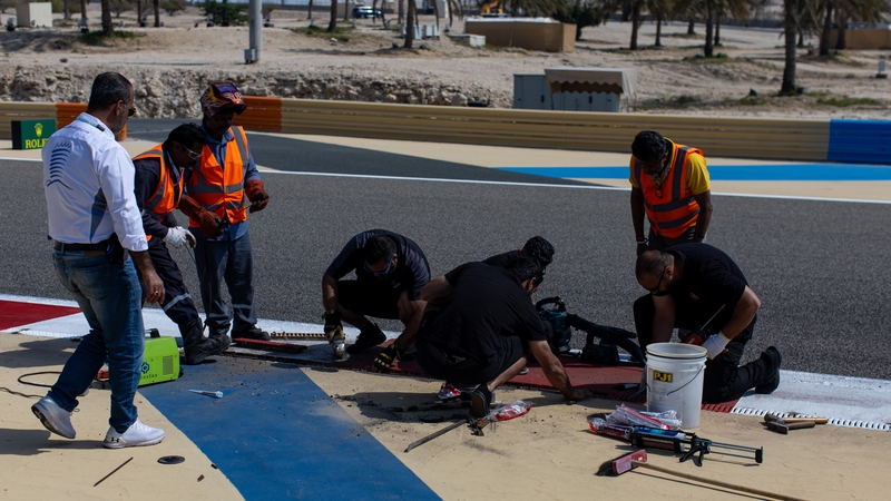 Bahrain track workers fix a loose drain cover that caused a red flag delay in Friday's morning testing